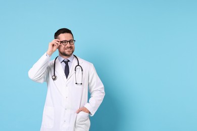 Smiling doctor on light blue background, space for text