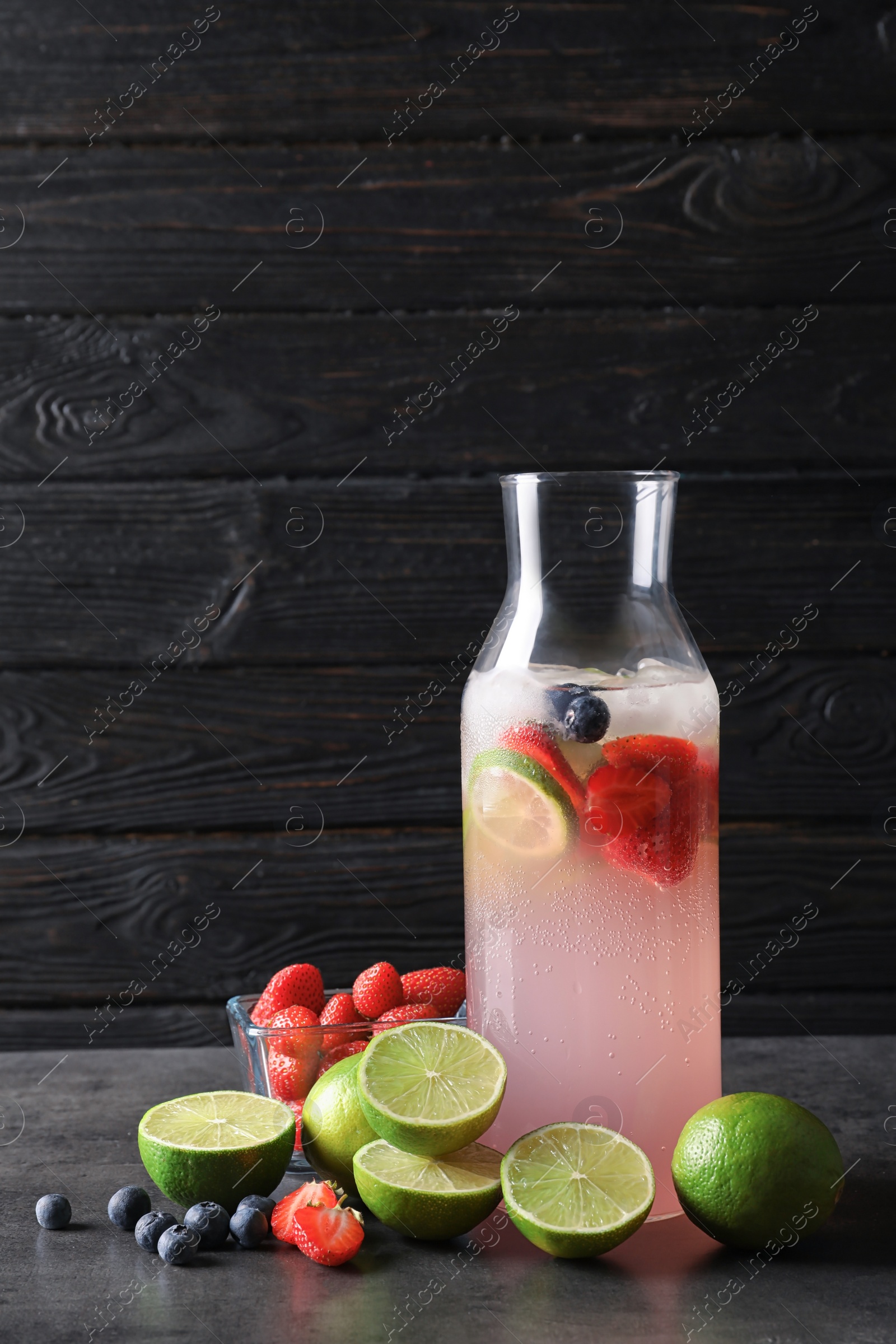 Photo of Natural lemonade with berries in bottle on table