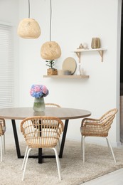 Photo of Table, chairs and vase of hydrangea flowers in dining room. Stylish interior