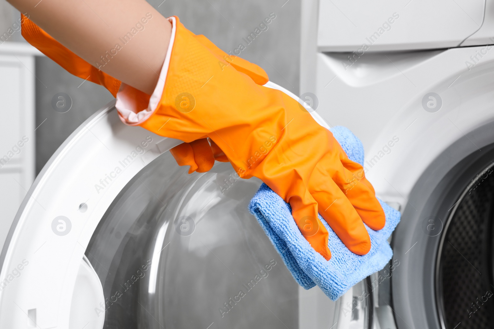 Photo of Woman cleaning washing machine with rag indoors, closeup