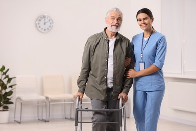 Photo of Smiling nurse supporting elderly patient in hospital, space for text