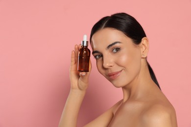 Photo of Young woman with bottle of essential oil on pink background. Space for text