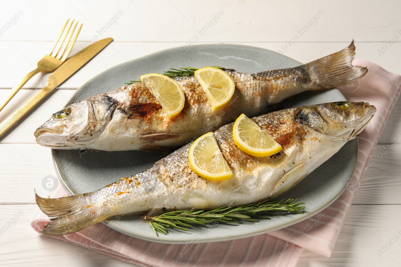 Photo of Delicious baked fish served on white wooden table