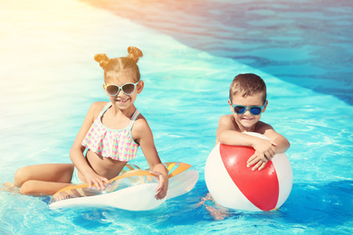 Cute little children with inflatable toys in swimming pool