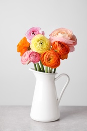 Photo of Beautiful ranunculus flowers in white jug on table