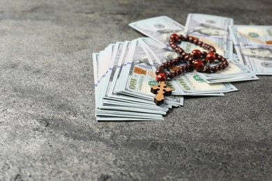 Photo of Wooden cross and money on grey table, closeup. Space for text