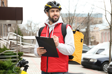 Courier with thermo bag and clipboard on city street. Food delivery service