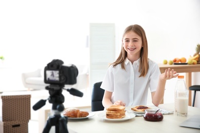 Photo of Cute teenage blogger with food recording video at home