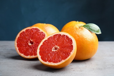 Fresh tasty grapefruits on table against color background