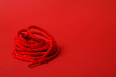 Photo of Bright shoe lace on red background. Space for text