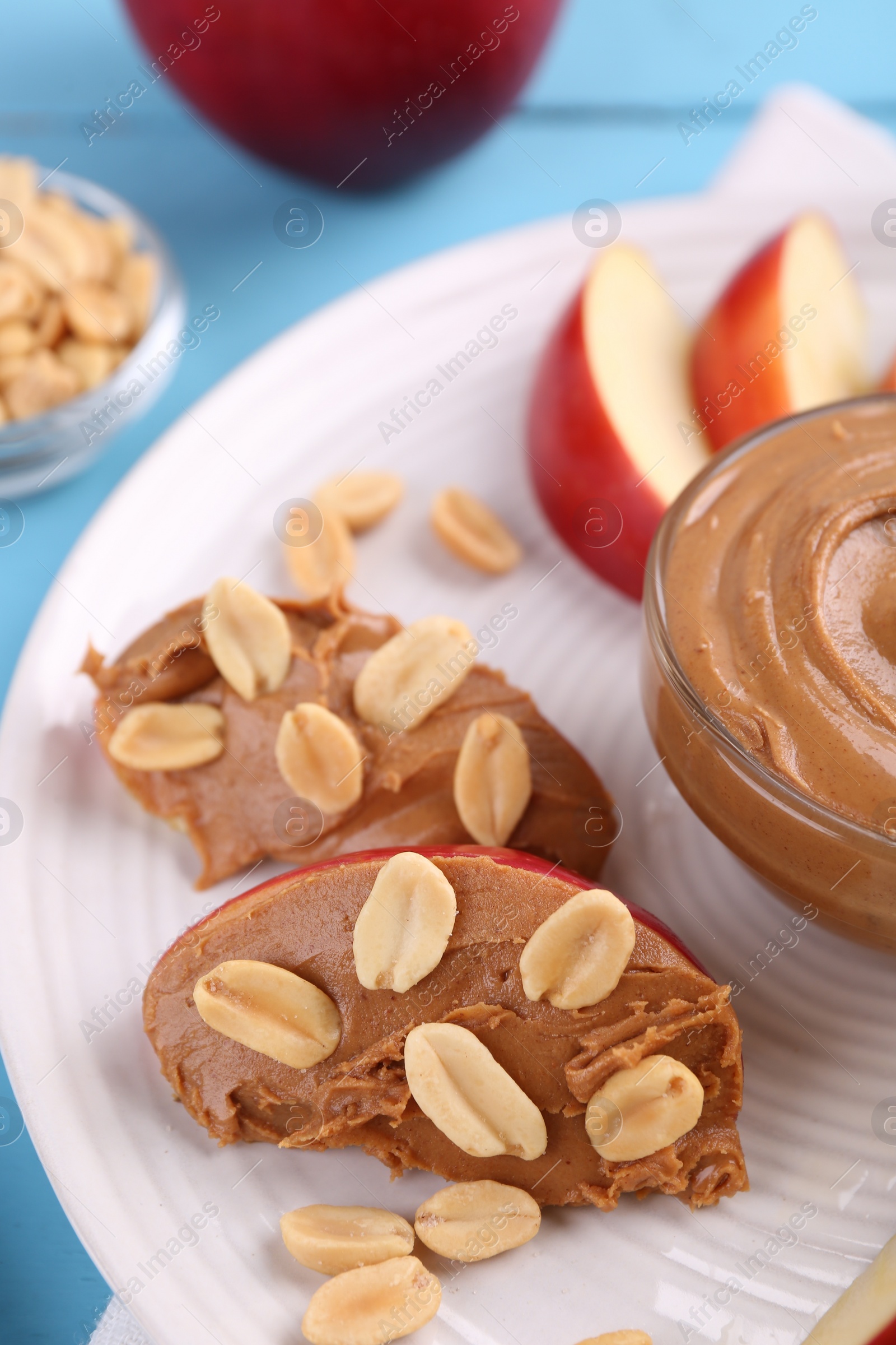 Photo of Slices of fresh apple with peanut butter and nuts on table, closeup