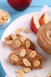 Slices of fresh apple with peanut butter and nuts on table, closeup