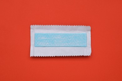 Unwrapped stick of tasty chewing gum on red background, top view