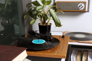 Photo of Stylish turntable with vinyl disc on table in room