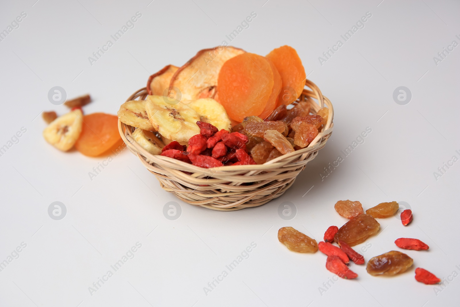 Photo of Wicker basket with different dried fruits on white background