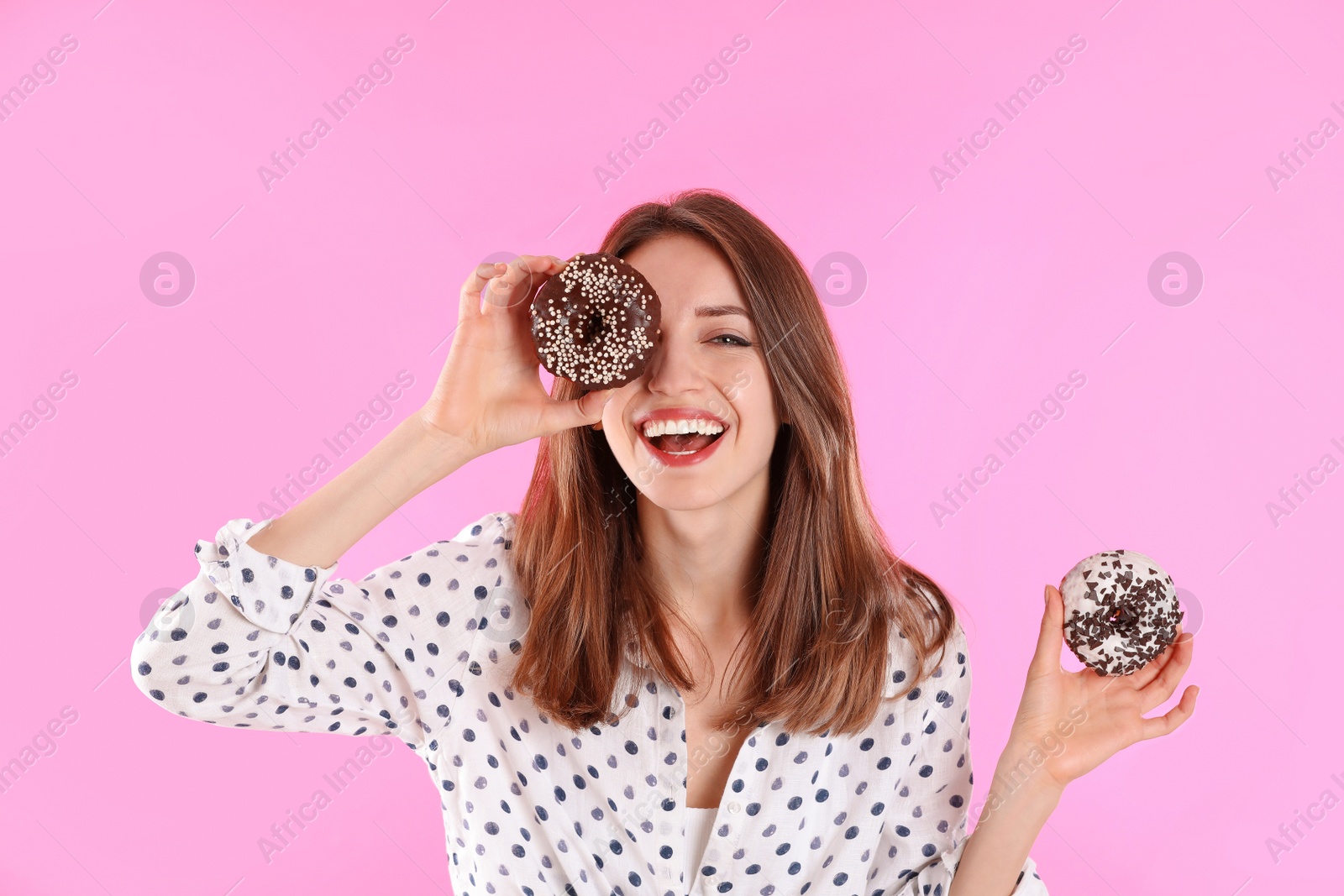 Photo of Beautiful young woman with donuts on light pink background