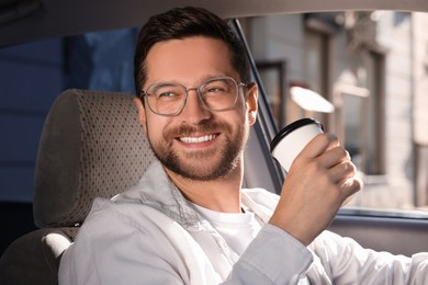 Photo of Coffee to go. Happy man with paper cup of drink in car