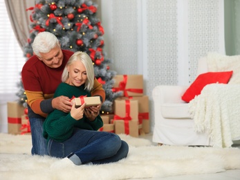 Happy mature couple with Christmas gift at home