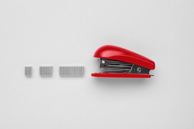 Photo of New bright stapler with staples on white background, fat lay. School stationery