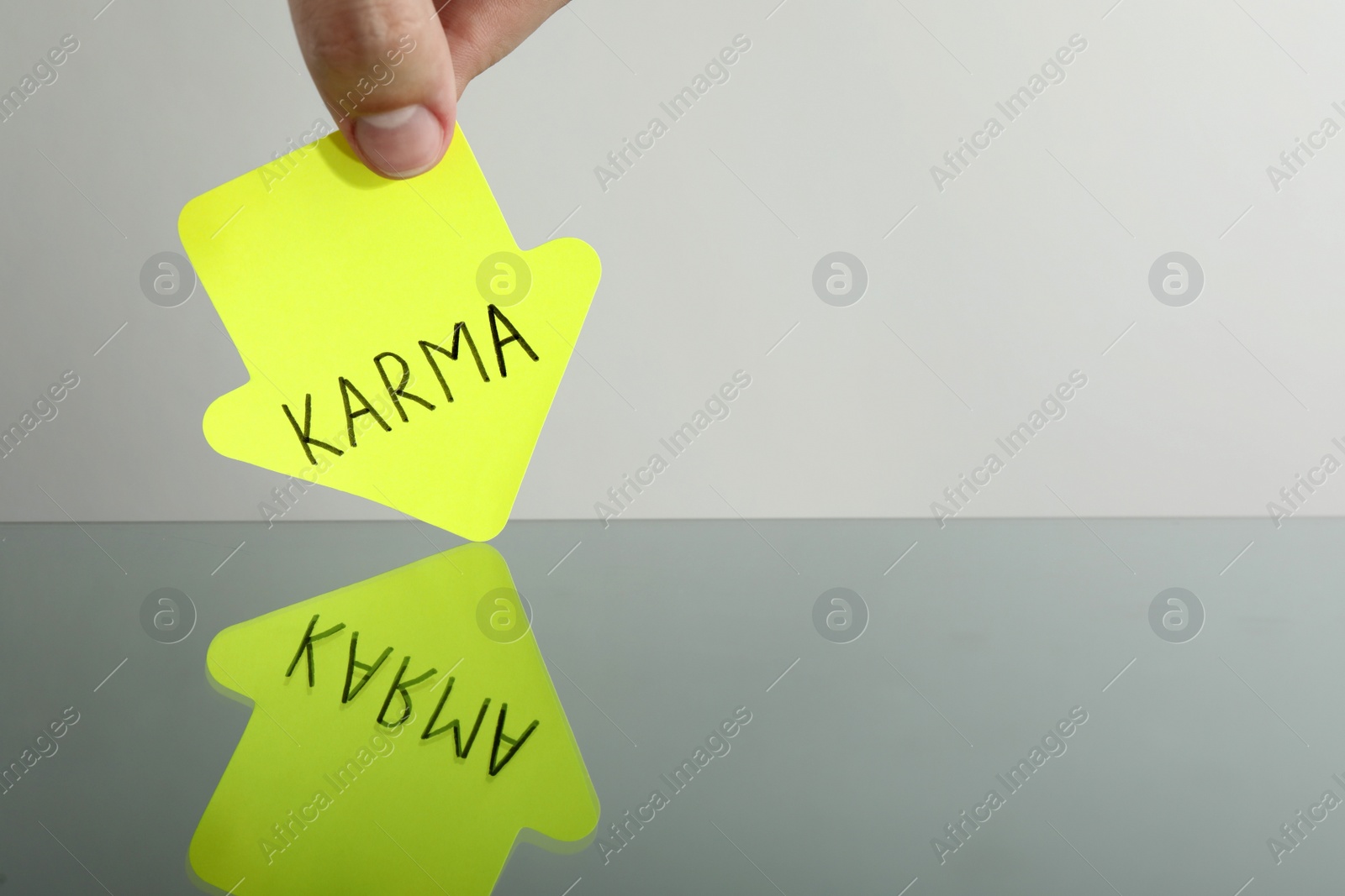 Photo of Woman holding arrow shaped sticker with word Karma above mirror, closeup. Space for text