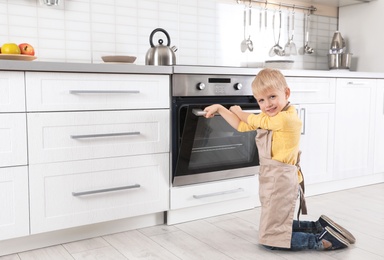 Little boy baking something in oven at home