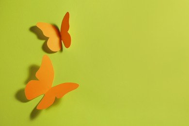 Image of Bright orange paper butterflies on light green background