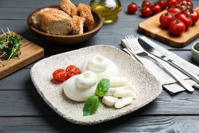 Photo of Delicious burrata cheese served on grey wooden table