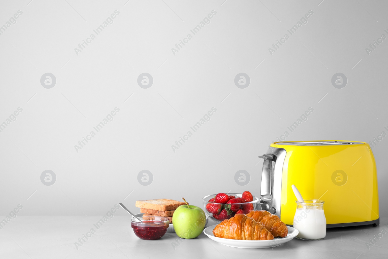 Photo of Healthy breakfast and modern toaster on light grey table, space for text