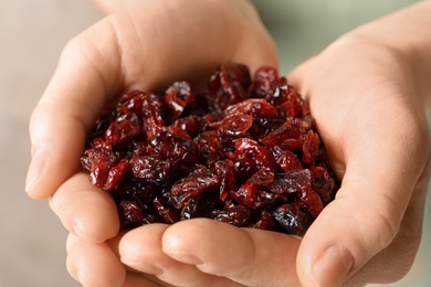 Photo of Woman holding handful of tasty cranberries on color background, closeup. Dried fruits as healthy snack