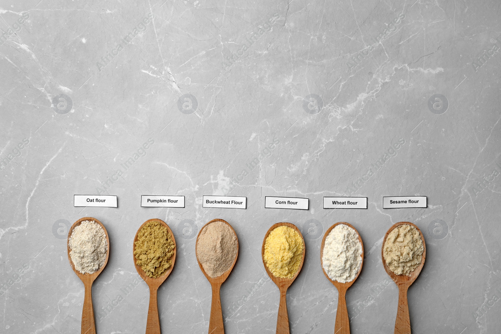 Photo of Spoons with different types of flour on light background