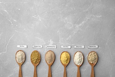 Spoons with different types of flour on light background