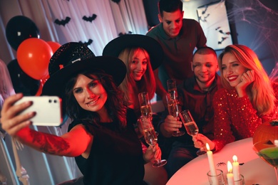 Photo of Group of friends taking selfie at Halloween party indoors