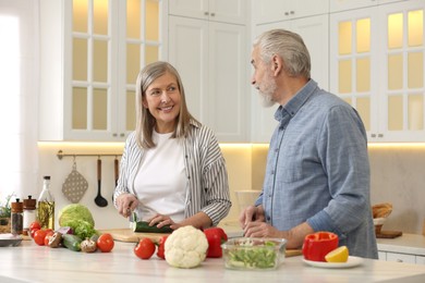 Happy senior couple cooking together in kitchen