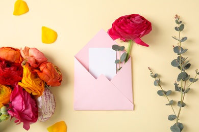 Photo of Flat lay composition with beautiful ranunculus flowers and card in envelope on color background. Space for text