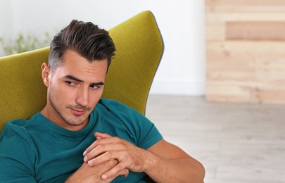 Photo of Portrait of handsome young man sitting in armchair at home