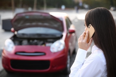 Photo of Young woman talking on phone near broken car outdoors