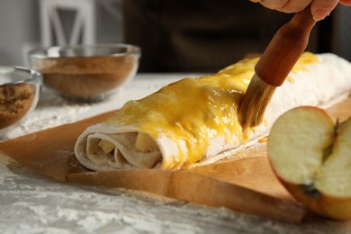 Photo of Woman making delicious apple strudel at table, closeup