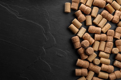Wine bottle corks on black table, flat lay. Space for text