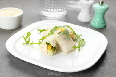 Photo of Delicious rolls wrapped in rice paper served on grey table
