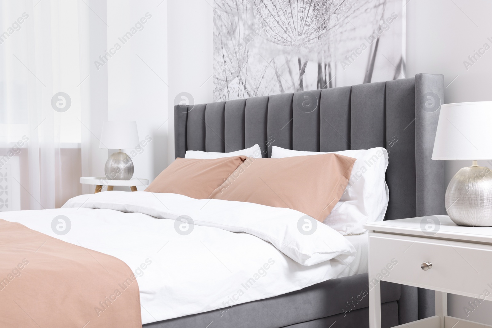 Photo of Comfortable bed and lamps on bedside tables in light room. Stylish interior