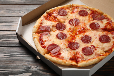 Hot delicious pepperoni pizza in cardboard box on wooden table, closeup