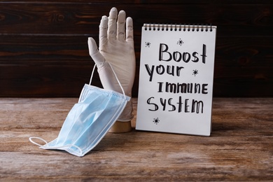 Photo of Notebook with Phrase Boost Your Immune System and medical items on wooden table