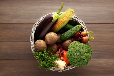 Photo of Basket with different fresh ripe vegetables on wooden table, top view. Farmer produce