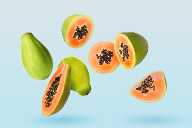 Image of Cut and whole papaya fruits falling on pale light blue background