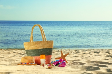 Composition with stylish beach accessories on sand near sea. Space for text