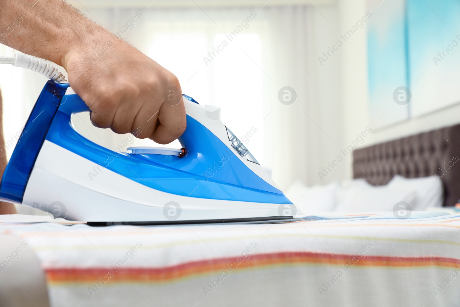 Photo of Man ironing clothes on board indoors, space for text. Household chores