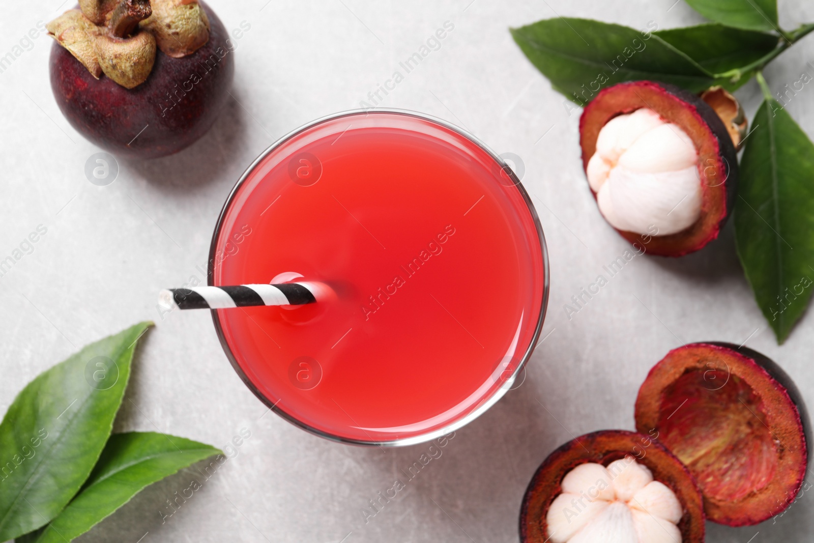 Photo of Delicious fresh mangosteen juice on light grey table, flat lay