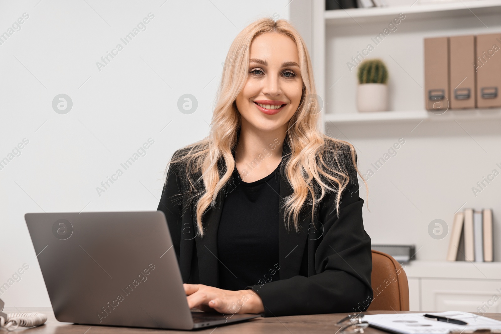 Photo of Happy secretary working with laptop in office