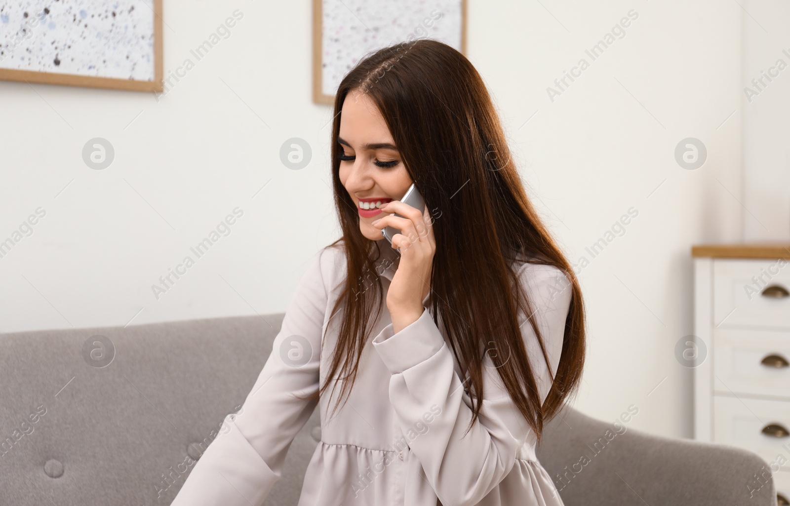 Photo of Happy woman talking on mobile phone indoors