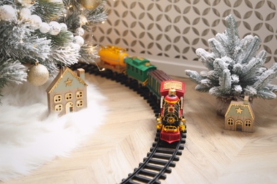 Photo of Toy train and railway near Christmas tree indoors